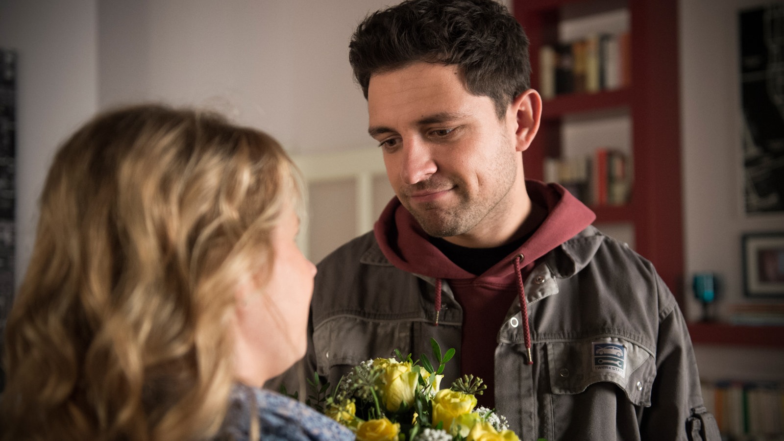 Nina hält einen Blumenstrauß und strahlt Enzo an