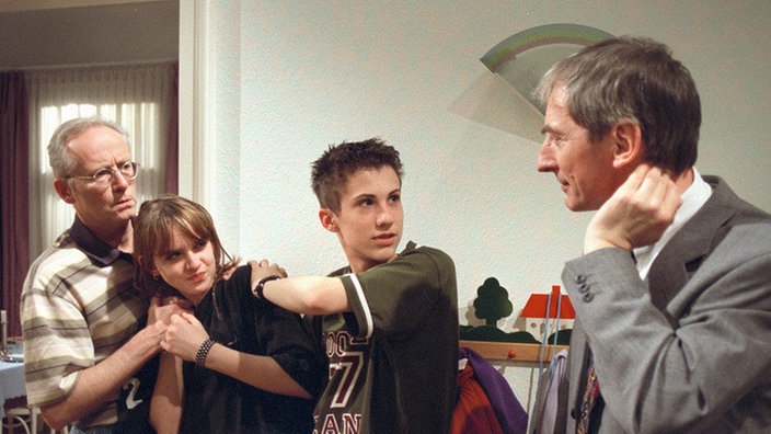 Nur Hans (Joachim Hermann Luger, links) erkennt den Ernst der Lage: Sein Vorgesetzter Hein (Harald Redmer) hat herausgefunden, dass sich Jack (Cosimsa Viola) illegal im Hause Beimer/Ziegler aufhält. Felix (Marc-Oliver Moro) versucht, seine Freundin vor dem Zugriff des Amtes zu schützen.