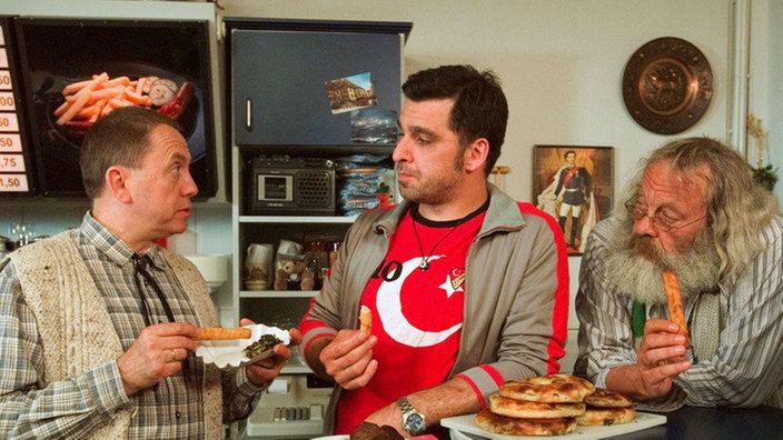 Olaf (Franz Rampelmann, links) interessiert sich neuerdings wieder für seinen Imbiss. Murat (Erkan Gündüz, Mitte) und Harry (Harry Rowohlt) sind erfreut über den seltenen Gast.