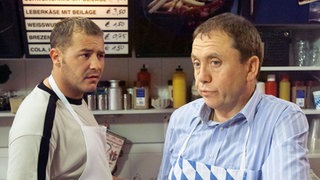 Olli (Willi Herren, links) hat starke Zweifel an dem Preis, den Olaf (Franz Rampelmann) für seine Verlobungsfeier im "Café Bayer" zahlen soll. Will Gabi Zenker mit dieser Preisvorstellung die Verlobung verhindern?