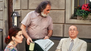 Panaiotis (Kostas Papanastasiou) belästigt mit seiner Sammelaktion Beate (Susanne Gannott) und Dr. Dressler (Ludwig Haas) beim Mittagessen.