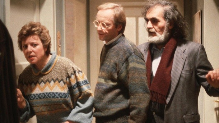 Panaiotis Sarikakis (Kostas Papanastasiou, rechts) ist gekommen um mit Onkel Franz zu sprechen, doch der hat sich eingeschlossen, wie Helga (Marie-Luise Marjan) und Hans (Joachim Hermann Luger) feststellen müssen.