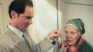Phil Seegers (Marcus Off) zeigt der entsetzten Else (Annemarie Wendl) den Fisch, den er im Treppenhaus aufgesammelt hat.