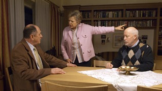 Professor Melchior (Jürgen Haug, links) hat gestanden, dass er Erich (Bill Mockridge) mit Medikamenten manipuliert hat. Helga (Marie-Luise Marjan) wirft den Arzt daraufhin aus der Wohnung.