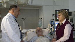 Professor Melchior (Jürgen Haug, links) macht Erich (Bill Mockridge) klar, dass ihm nur ein Spenderherz helfen kann. Helga (Marie-Luise Marjan) steht ihrem Mann bei.