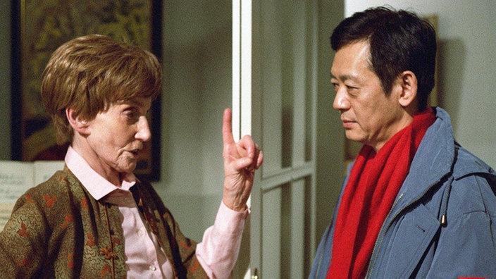 Rosi (Margret van Munster) ist empört: Gung (Amorn Surangkanjanajai) hat seinen Job verloren und steht demnächst auf der Straße.