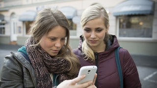 Sabine zeigt Lea etwas auf ihrem Smartphone