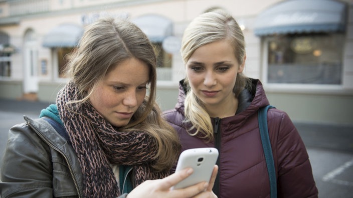 Sabine zeigt Lea etwas auf ihrem Smartphone