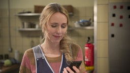 Sandra schaut lächelnd auf ihr Handy