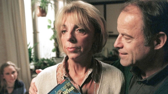 Scholz (Knut Hinz) überrascht Berta (Ute Mora, re) mit einer Reise nach Wien. Lisa (Sontje Peplow) hört mit einer Mischung aus Neugier und Entsetzen zu.