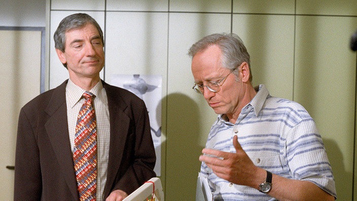 Schwerer Schlag ins Kontor: Herr Hein (Harald Redmer) streicht den Jahresurlaub von Hans Beimer (Joachim Hermann Luger, rechts) und macht damit alle Pläne zunichte, Jack in Ruhe in die Familie zu integrieren.