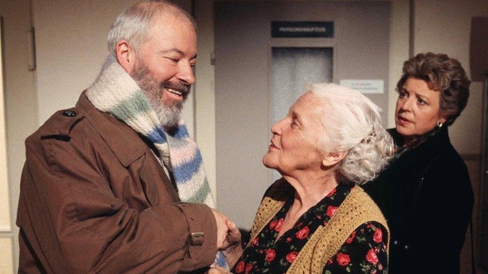 Selbst Else (Annemarie Wendl, Mitte) heißt Erich (Bill Mockridge) in der Lindenstraße willkommen. Auch Helga (Marie-Luise Marjan) freut sich.