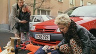 Tom liegt auf der Straße und Pat, Helga und Sarah stehen daneben