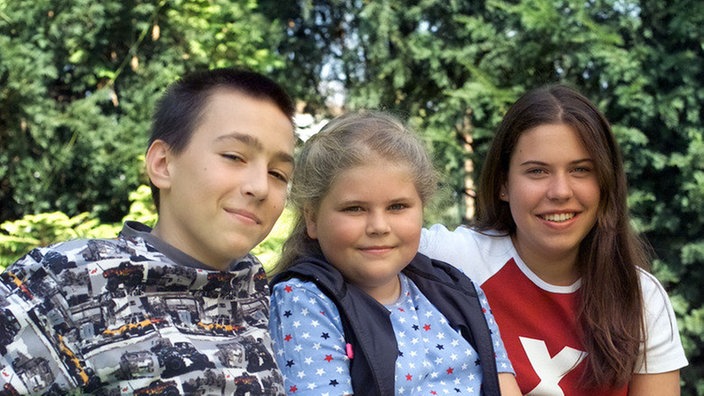 Tom, Sophie und Sarah sitzen auf einer Bank