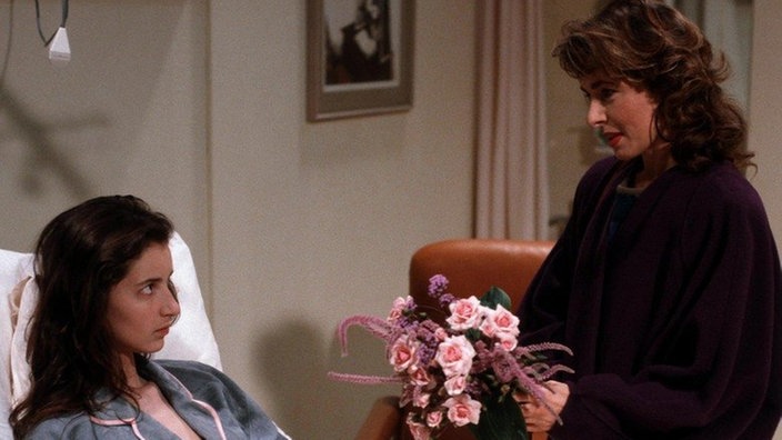 Vera (Ria Schindler, rechts) besucht Dominique (Brigitte Annessy) im Krankenhaus, um mit ihr über Mourrait zu sprechen.