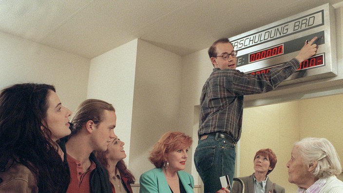 Volksauflauf im Treppenhaus: Philipp bringt seine "Schuldenuhr" an (v.l.: Clelia Sarto, Moritz A. Sachs, Rebecca Siemoneit-Barum, Marianne Rogée, Philipp Neubauer, Inga Abel, Annemarie Wendl).