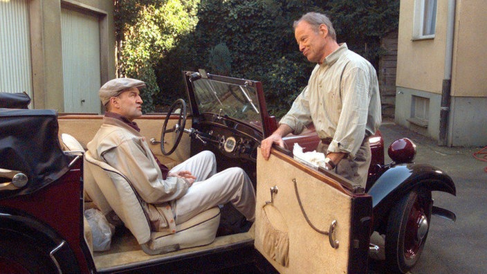 Voller Stolz präsentiert Hajo (Knut Hinz, rechts) einem Mann namens Ritter (Axel Gottschick) seinen Oldtimer. Die Freude währt allerdings nicht lange.