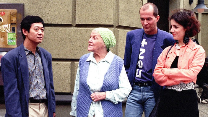 Vor dem "Akropolis" muss sich Gung (Amorn Surangkanjanajai, links) von Else (Annemarie Wendl, links) belehren lassen. Carsten (Georg Uecker) und Beate (Susanne Gannott) hören amüsiert zu.