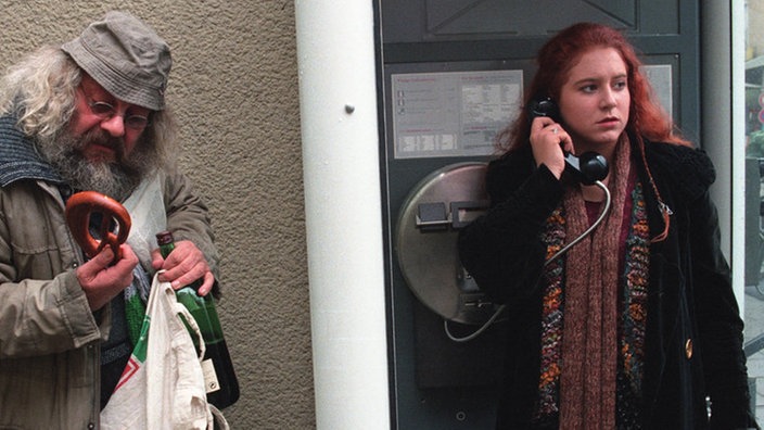 Während Iffi (Rebecca Siemoneit-Barum) telefonisch ein Date ausmacht, kümmert sich Harry (Harry Rowohlt) um die frischen Brezeln.