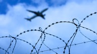 Das Bild zeigt ein Flugzeug das über einen Stacheldraht fliegt.