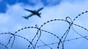 Das Bild zeigt ein Flugzeug das über einen Stacheldraht fliegt.
