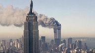 Die Zwillingstürme des World Trade Centers brennen hinter dem Empire State Building (11.09.2001)
