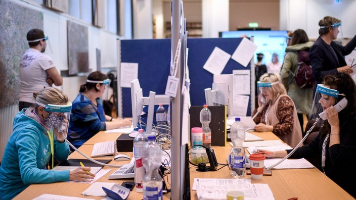 Mitarbeiter*innen telefonieren im Gesundheitsamt Berlin-Mitte.
