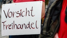 Ein Demonstrant mit einem Schild mit der Aufschrift "Vorsicht Freihandel" um den Hals