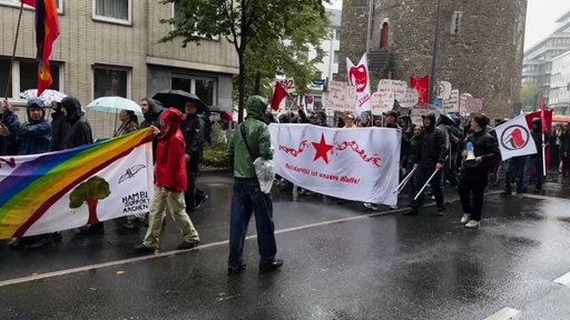 Demonstrierende stehen auf der Straße und halten Schilder und Banner hoch 