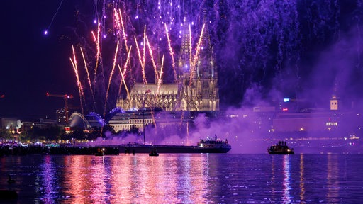 Ein Feuerwerk schießt in den Himmel, im Hintergrund der Kölner Dom