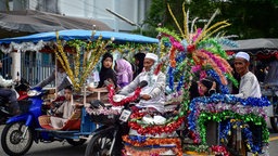 Thailändische Muslime fahren auf prächtig geschmückten Fahrzeugen durch die Straßen
