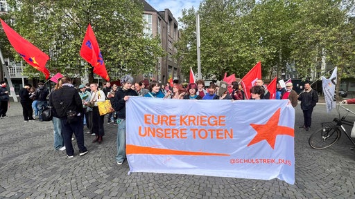 Schüler und Schülerinnen halten einen Banner hoch mit: Eure Kriege Unsere Toten
