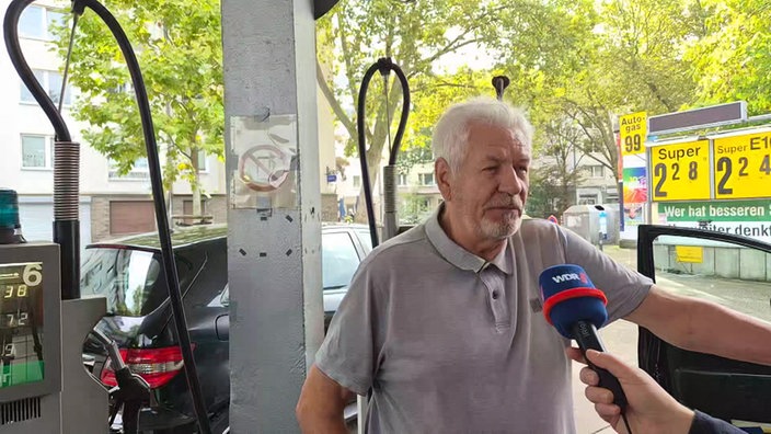 Ein Mann wird bei einer Tankstelle interviewt