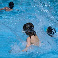 Kinder springen im Sommerbad Neukölln ins Schwimmbecken. 