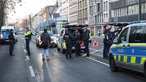 Einsatzkräfte der Polizei stehen auf einer Straße