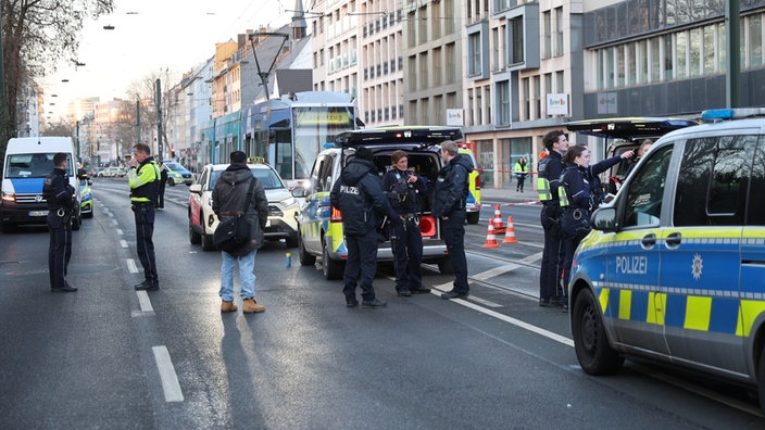 Einsatzkräfte der Polizei stehen auf einer Straße