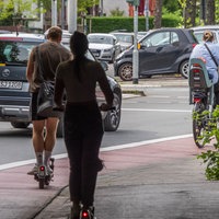  Ein Mann und eine Frau fahren auf E-Scootern auf einem Fahrradweg