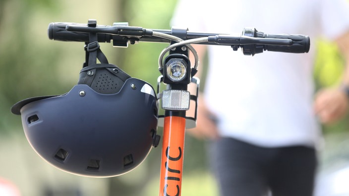 Ein E-Scooter steht samt Helm fahrbereit auf der Straße