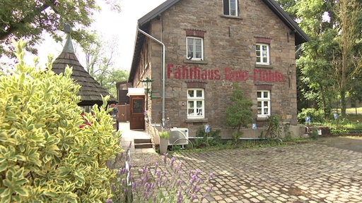 Steinerner Bau, dreigeschossig mit Satteldach, Aufschrift auf Mauer: Fährhaus Rote Mühle