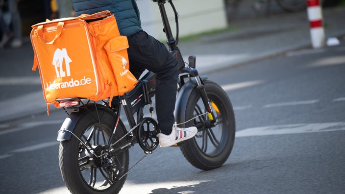 Ein Fahrer für den Essenslieferdienst Lieferando fährt mit einem Fatbike