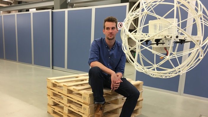 Junger Mann mit einer DRohne in Kugelform