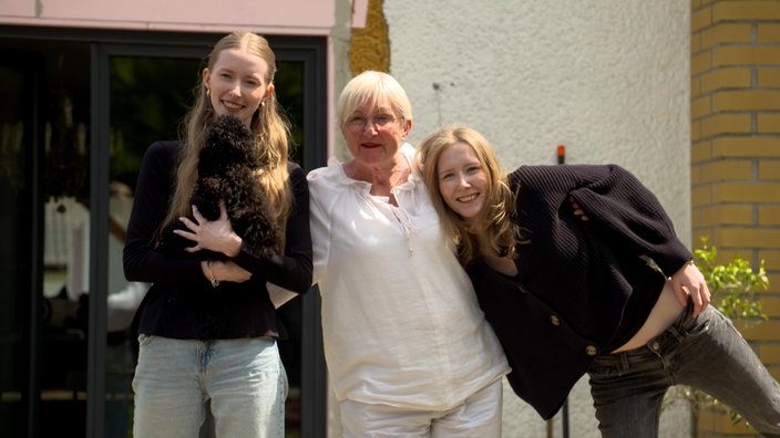 Beate Jankowiak und ihre Töchter stehen Arm in Arm und lachen in die Kamera.
