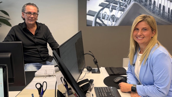 Sandro und Claudia sitzen gemeinsam an Schreibtischen im Büro.