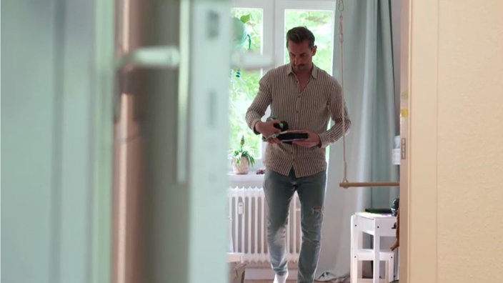 Ein Mann geht durch ein Kinderzimmer und hält Spielzeug in den Händen