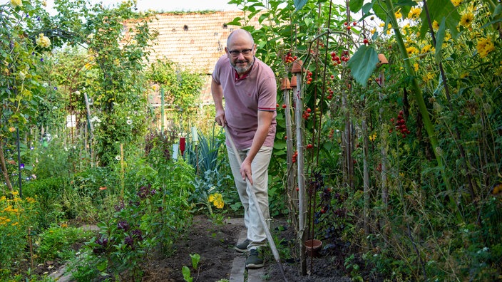 Peter Hamburger mit einer Gartenharke. 