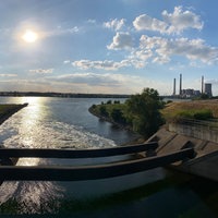 Eine Flussmündung, im Vordergrund laufen zwei Röhren über das Wasser, im Hintergrund ein Kraftwerk