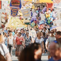 Viele Menschen gehen zwischen Jahrmarktsbuden durch