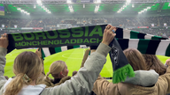 Während der Hymne halten Fans im Stadion ihre Schals in die Höhe.