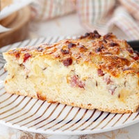 Ein Stück Zwiebelkuchen. Präsentiert auf einem Teller mit Gabel.