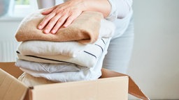 Frau packt Kleidung für eine Kleiderspende in einen